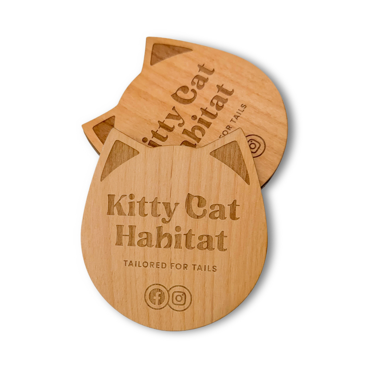 Stack of wooden cat head drink coasters showing the engraved logo on a light background.