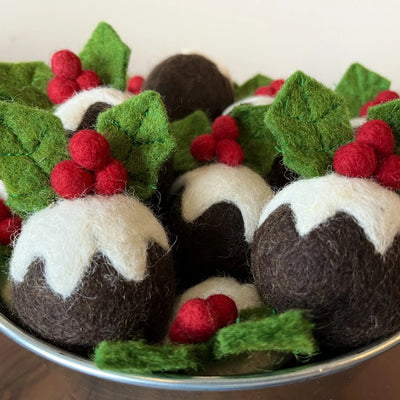 Felted wool Christmas pudding cat toy balls topped with holly leaves and red berries, piled in a metal bowl
