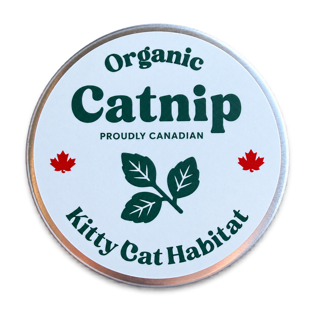 A round metal tin lid with a white label reading 'Organic Catnip' and 'Kitty Cat Habitat,' featuring green text and leaf graphics, red maple leaves, and 'Proudly Canadian' text, on a black background.