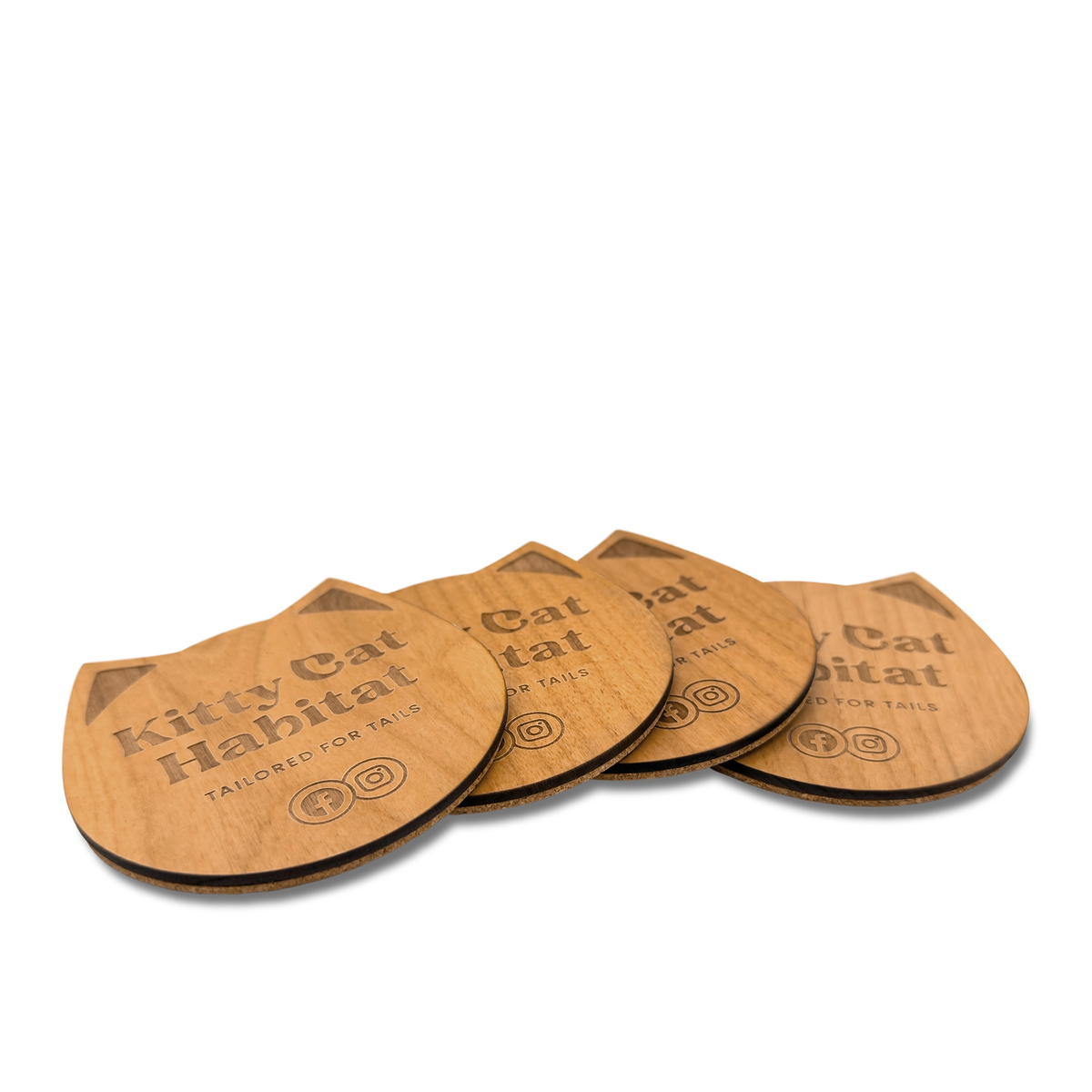 Group of wooden cat head drink coasters fanned out to show the engraved design on a light background.