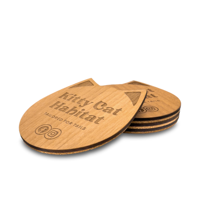 Small stack of wooden cat head drink coasters viewed from the side on a light background.