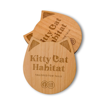 Stack of wooden cat head drink coasters showing the engraved logo on a light background.