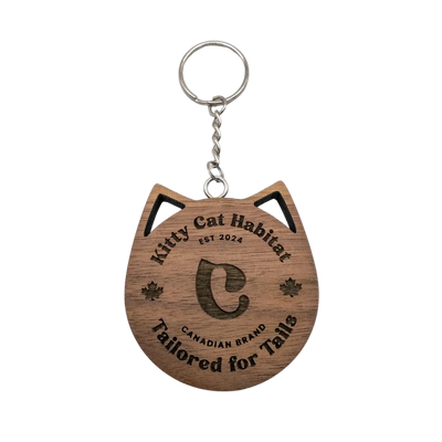Walnut wooden cat head keychain with Kitty Cat Habitat logo engraving on a light background.