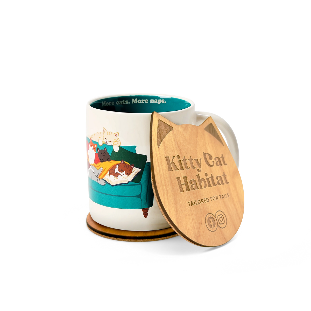 A ceramic mug with a colorful cat-themed illustration sits beside a wooden cat head shaped coaster. The lid is engraved with the text 'Kitty Cat Habitat' and 'TAILORED FOR TAILS'.